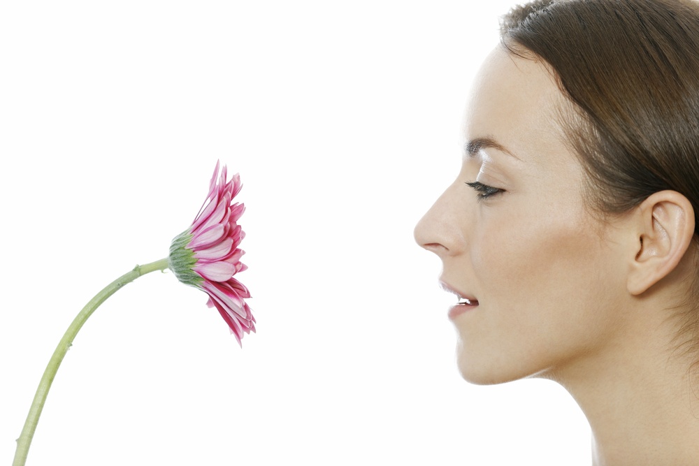 Attractive woman holding a red flower near her face