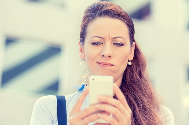 Closeup side profile portrait upset sad skeptical unhappy serious woman talking texting on phone displeased with conversation isolated city background. Negative human emotion face expression feeling.jpeg
