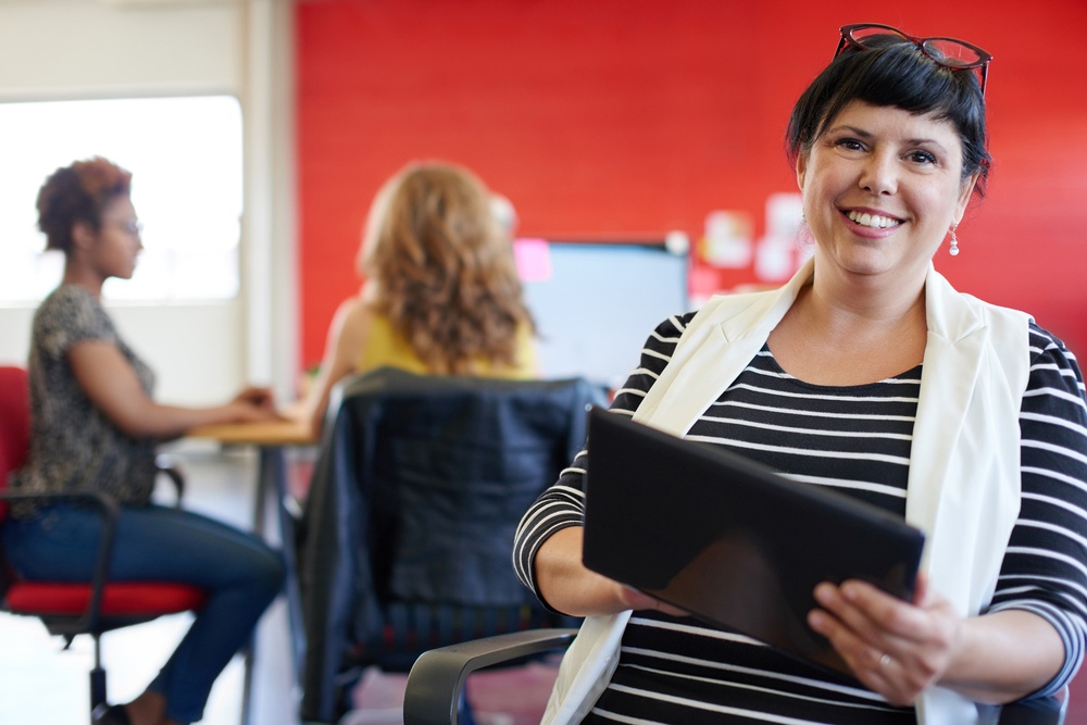 Confident female designer working on a digital tablet in red creative office space