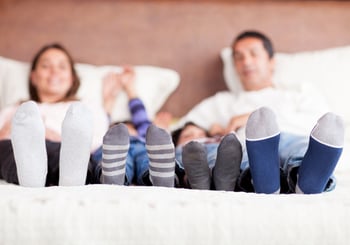 Family lying in bed together - focus on feet