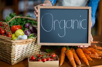 Female staff holding organic sign board in supermarket