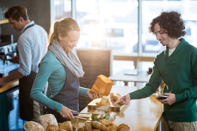 Female waitress packing sandwich in paper bag at cafx92xA9