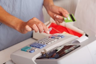 Midsection of saleswoman holding credit card while using ETR machine at boutique counter.jpeg