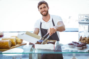 Smiling worker prepares orders at the bakery